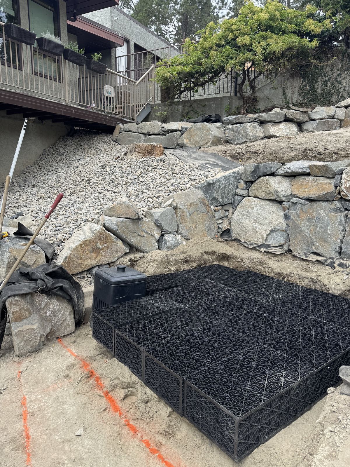 Black drainage chambers installed behind a stacked rock retaining wall